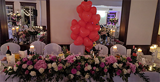 Wedding reception table with pink roses and red heart balloons