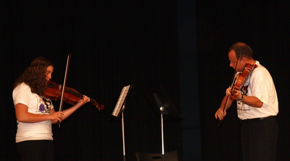 Violin student performing on stage alongside teacher Peter Swic
