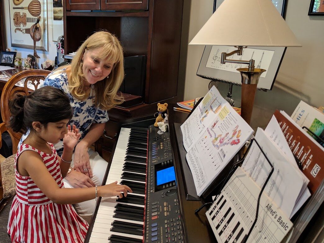 Young student playing a digital piano during a Piano Exploring lesson with her teacher