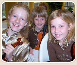 Young violin students smiling at a performance