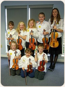Charlotte Strings Academy students with violins in a group photo