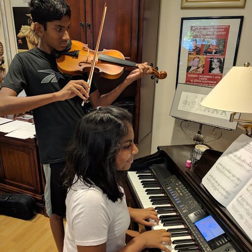 Two students playing violin and viola at the piano